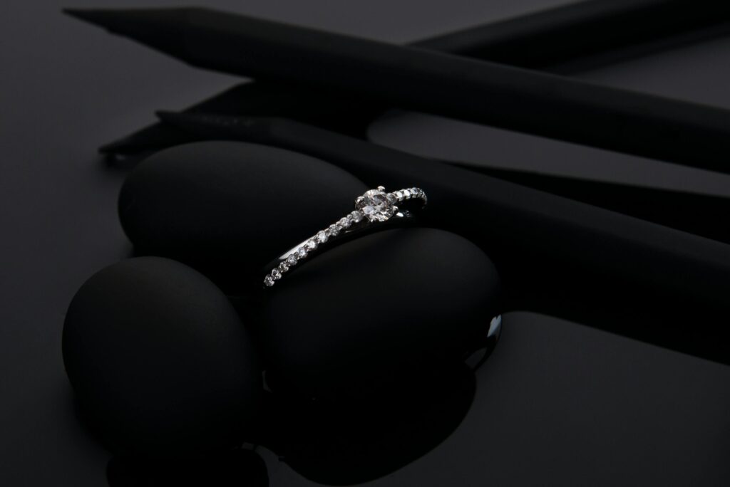 Sophisticated diamond engagement ring displayed stylishly on smooth black stones, perfect for luxury and jewelry themes.
